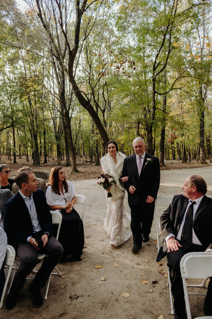 Bride wearing BHLDN wedding gown walking down the aisle during Ceremony in Deer Forrest at Southwick's Zoo Mendon