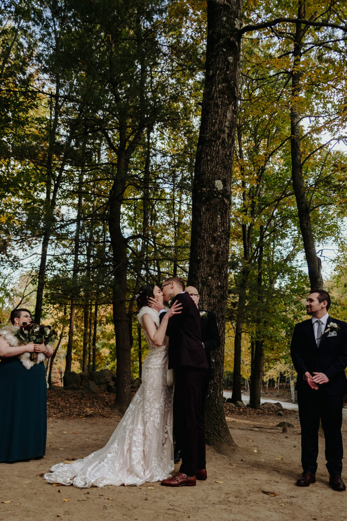 Bride and groom share first kiss during Ceremony in Deer Forrest at Southwick's Zoo Mendon
