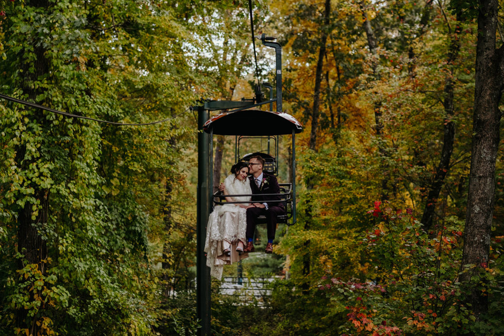 Bride wearing BHLD wedding Gown and groom wearing Indochino suit on the sky safari chairlift at Southwick's Zoo Mendon MA