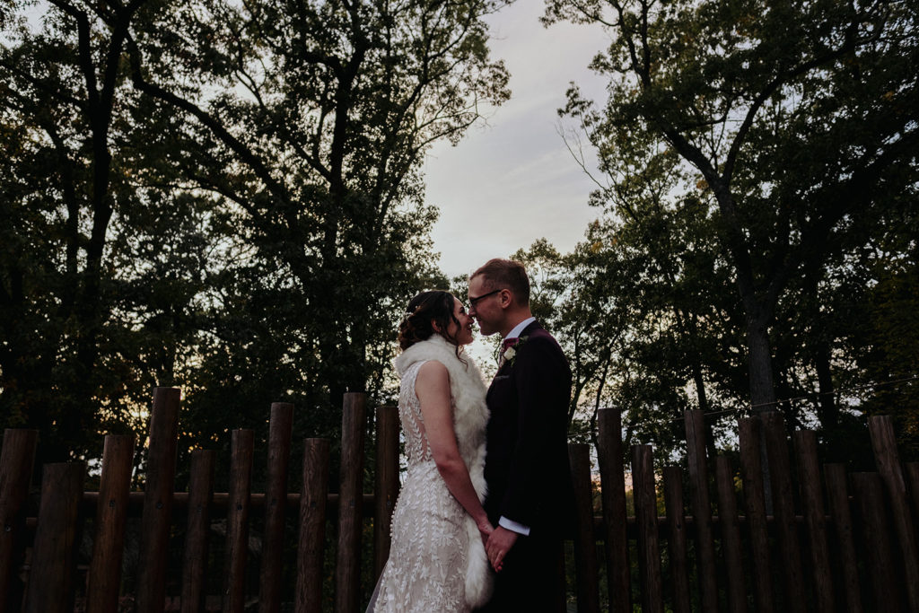 Bride wearing BHLDN gown and Groom wearing indochino suit pose for portrait at Southwick's Zoo Mendon MA