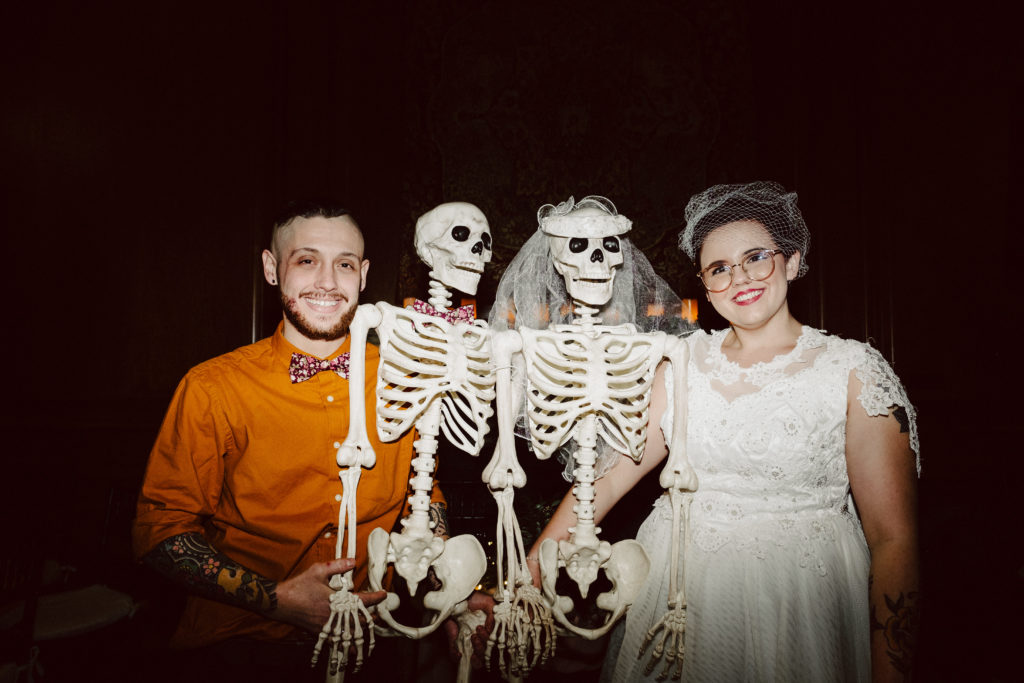 Bride and Groom pose with Bride and Groom Skeletons during Halloween Themed wedding at The Dane Estate