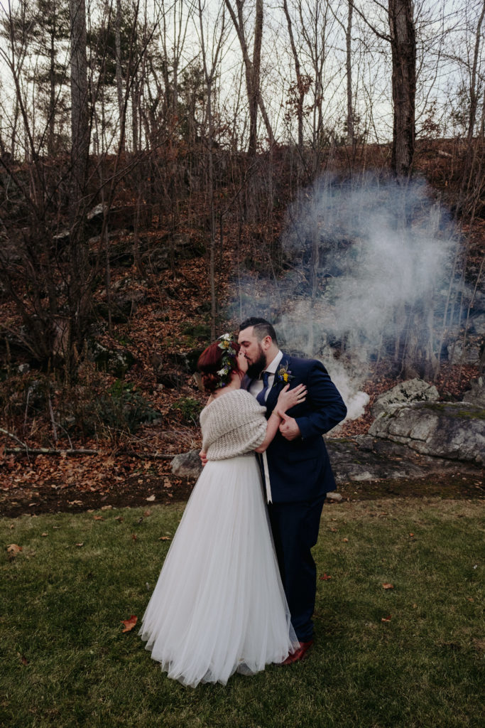 Bride and groom kiss as smoke bomb goes off behind them
