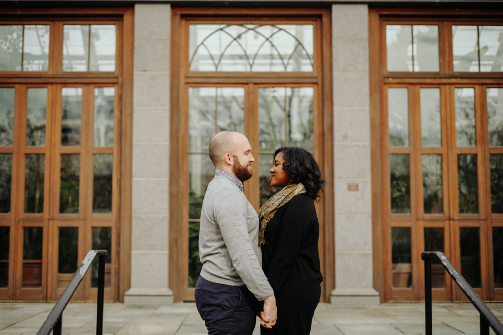Couple pose infront of greenhouse at Tower Hill Botanic Garden Engagement Session