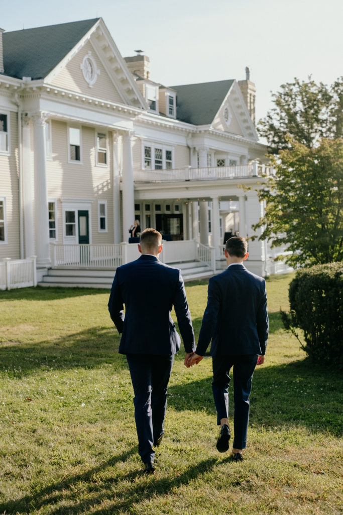 Two Grooms Walk hand in hand towards The Endicott Estate during Wedding
