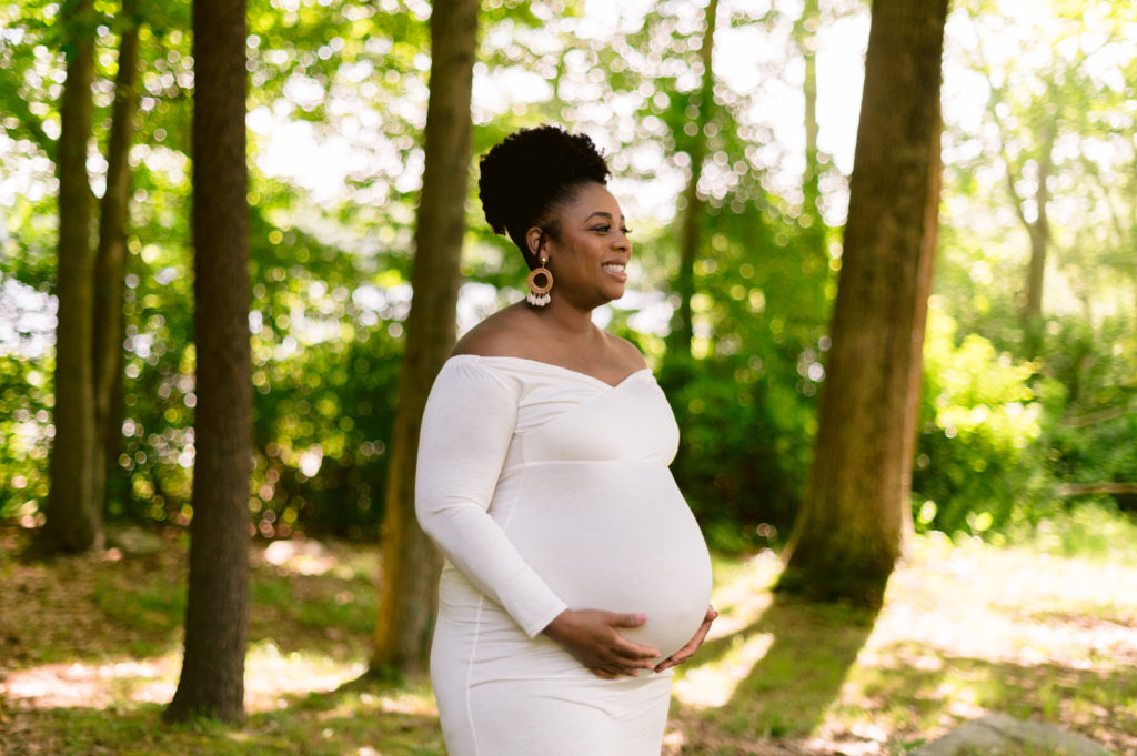 Expectant mother smiles during maternity session in Lincoln Woods state park rhode island