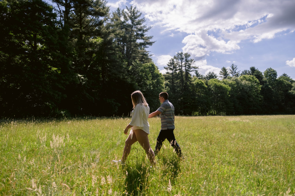 Couple walk hand in hand in field during borderland state park engagement session