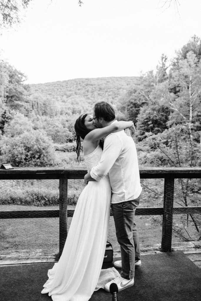 Bride wearing bhldn dress and groom share first kiss during ceremony at Berkshires Elopement