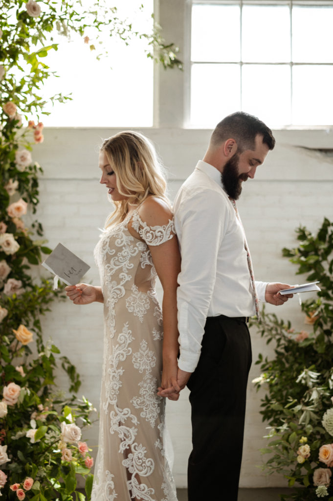 Bride and groom first touch during boho elopement at Tannery Loft in Massachusetts