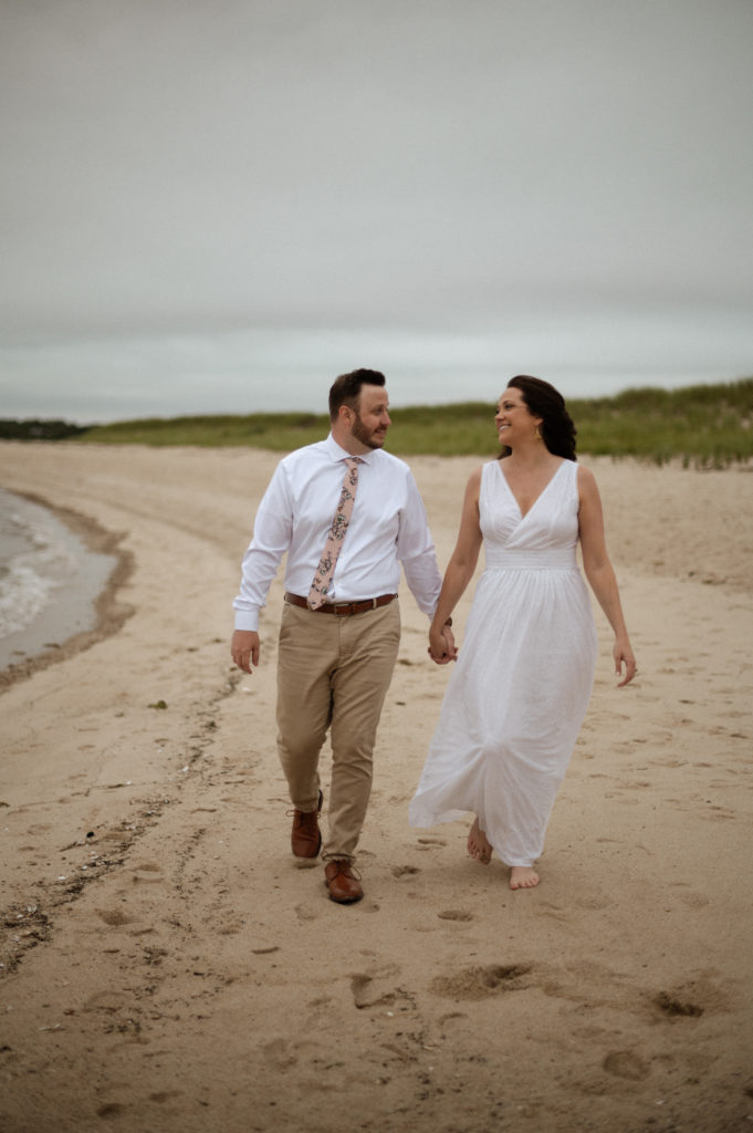 Bride and groom walk along sand at Crosby Landing Beach Elopement