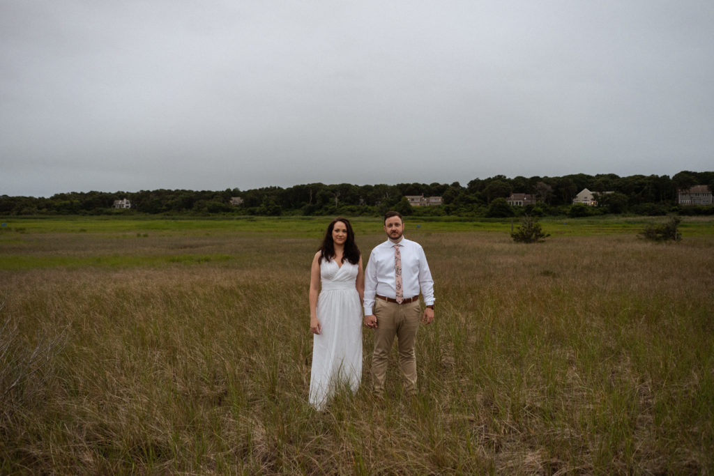 Bride and groom stand in wetlands at Crosby Landing Beach Massachusetts Cape Cod Minimony