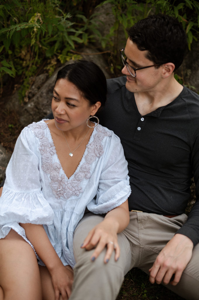 Couple sits together during engagement photos at Stonehurst