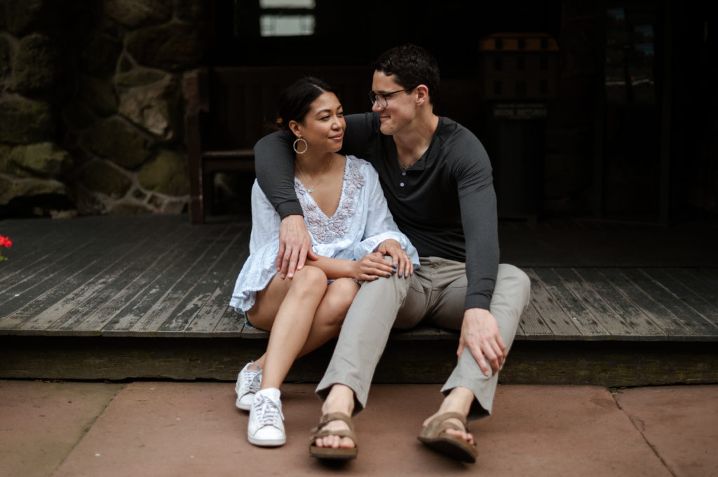 Couple sits together during engagement photos at Stonehurst