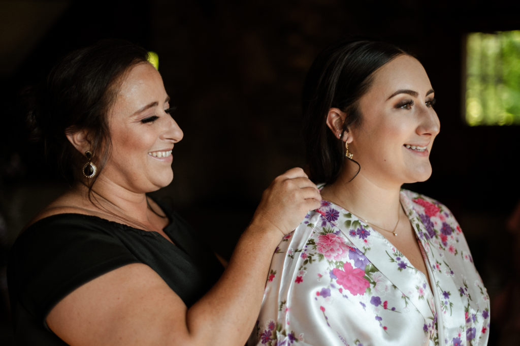 Mother of the bride puts fastens necklace for bride as she gets ready
