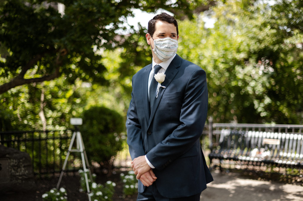 Groom wearing face mask waits for bride during covid wedding