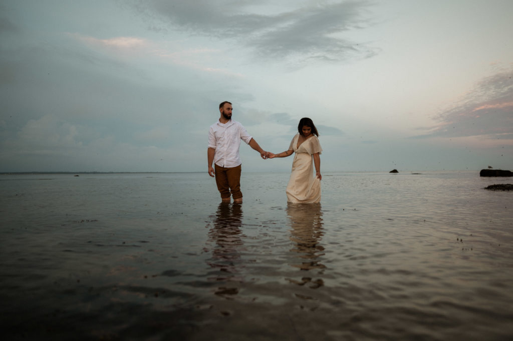 Romantic Sunset anniversary session on Gooseberry Island in Westport Massachusetts, couple in the water with woman wearing BHLDN dress