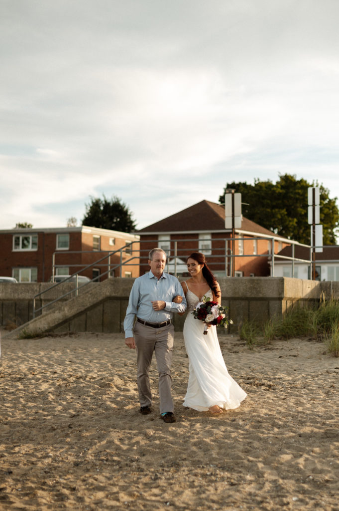 Bride walks down beach with dad during minimony on Boston's Wollaston Beach - Boston Wedding Photographer Jemima Richards