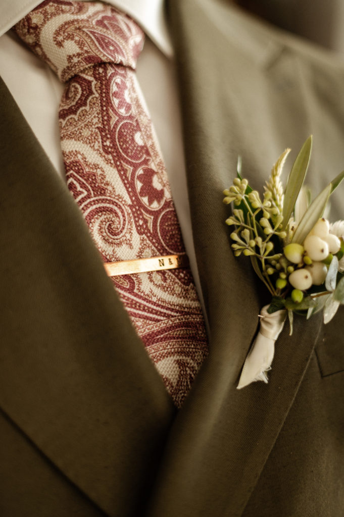 Glasses wearing groom wearing green double breasted suit with succulent details