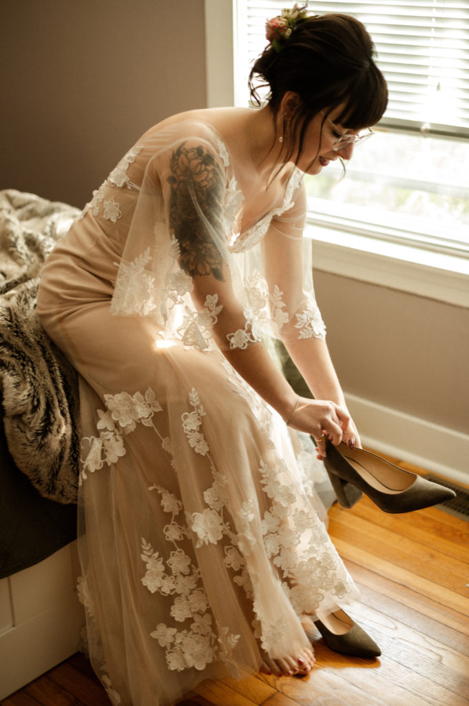 Glasses wearing bride getting into her bhldn wedding gown