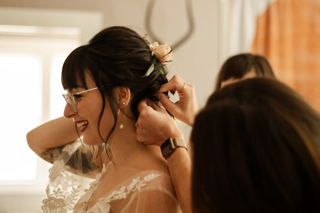Glasses wearing bride getting into her bhldn wedding gown