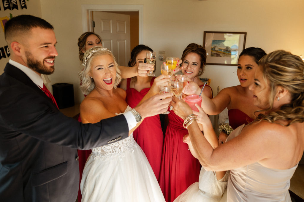 Bride cheers with wedding party before first look at The Lighthouse Inn wedding on Cape Cod Massachusetts