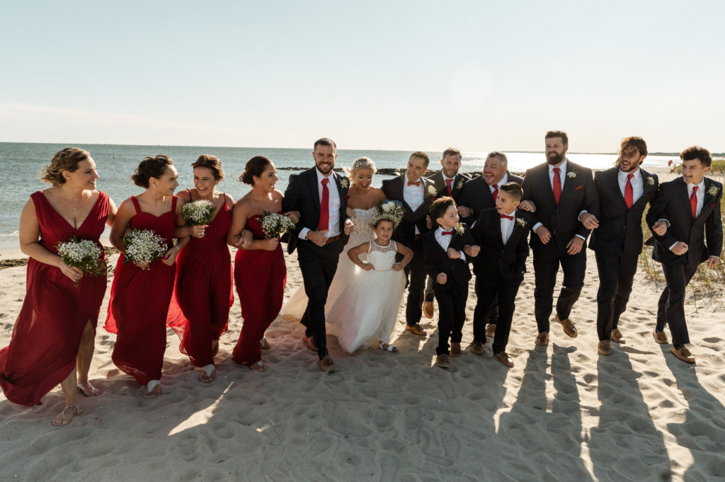 Entire wedding party with bride and groom on the beach for Wedding at the Lighthouse inn on Cape Cod