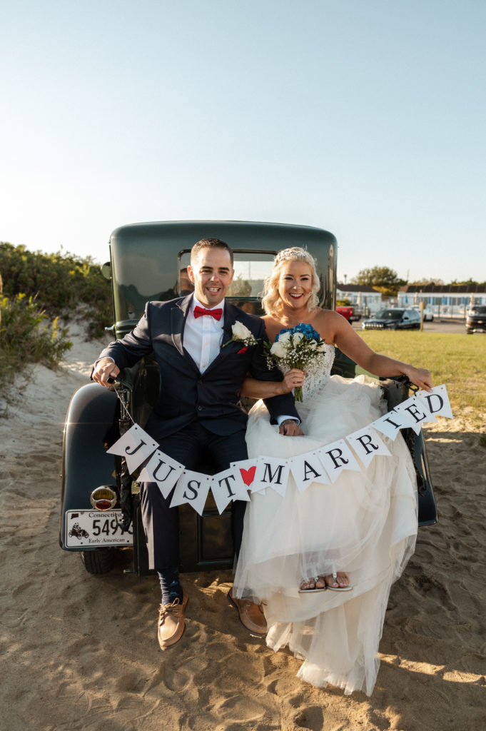 Bride and groom on back of vintage truck with Just Married Sign