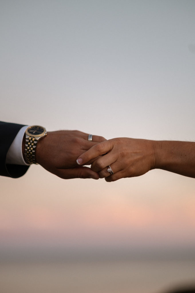close up of bride and groom's hands at sunset to show wedding rings during Cape Cod wedding at The Lighthouse Inn