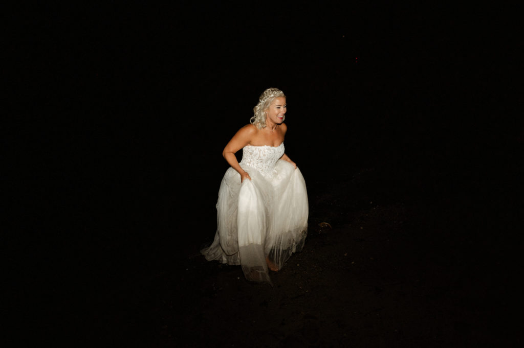 Bride runs into ocean at the end of wedding in bridal gown at The Lighthouse Inn West Dennis Cape Cod