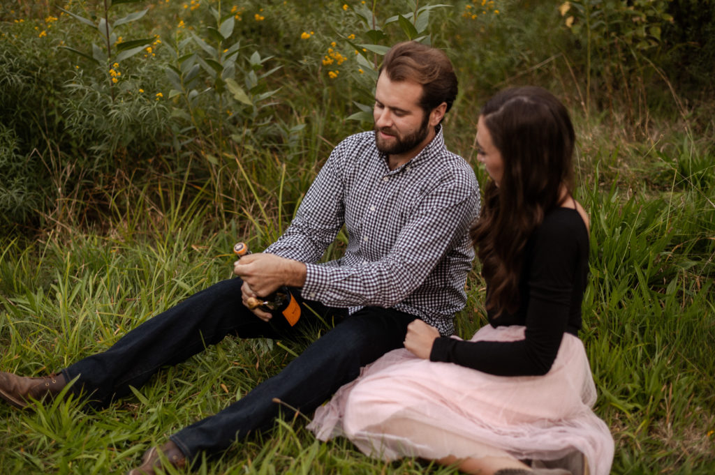 Couple pop champagne during engagement session at Arnold Arboreutm in Boston