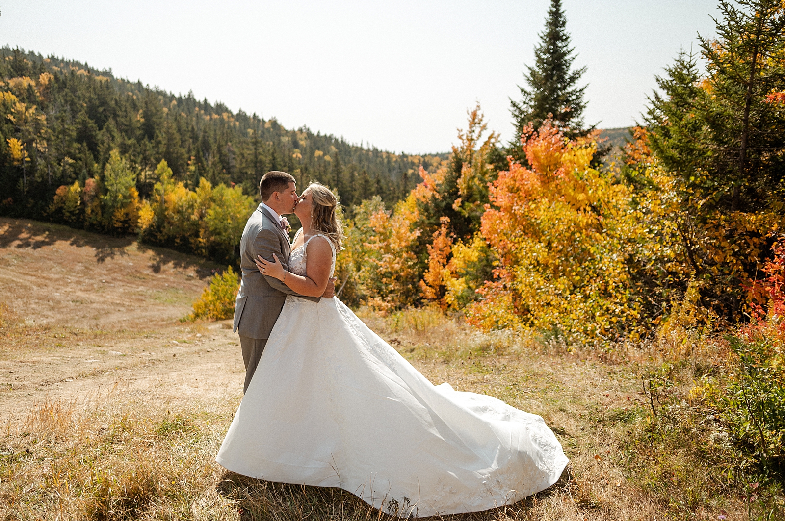 Bride and Groom kissing by fall trees