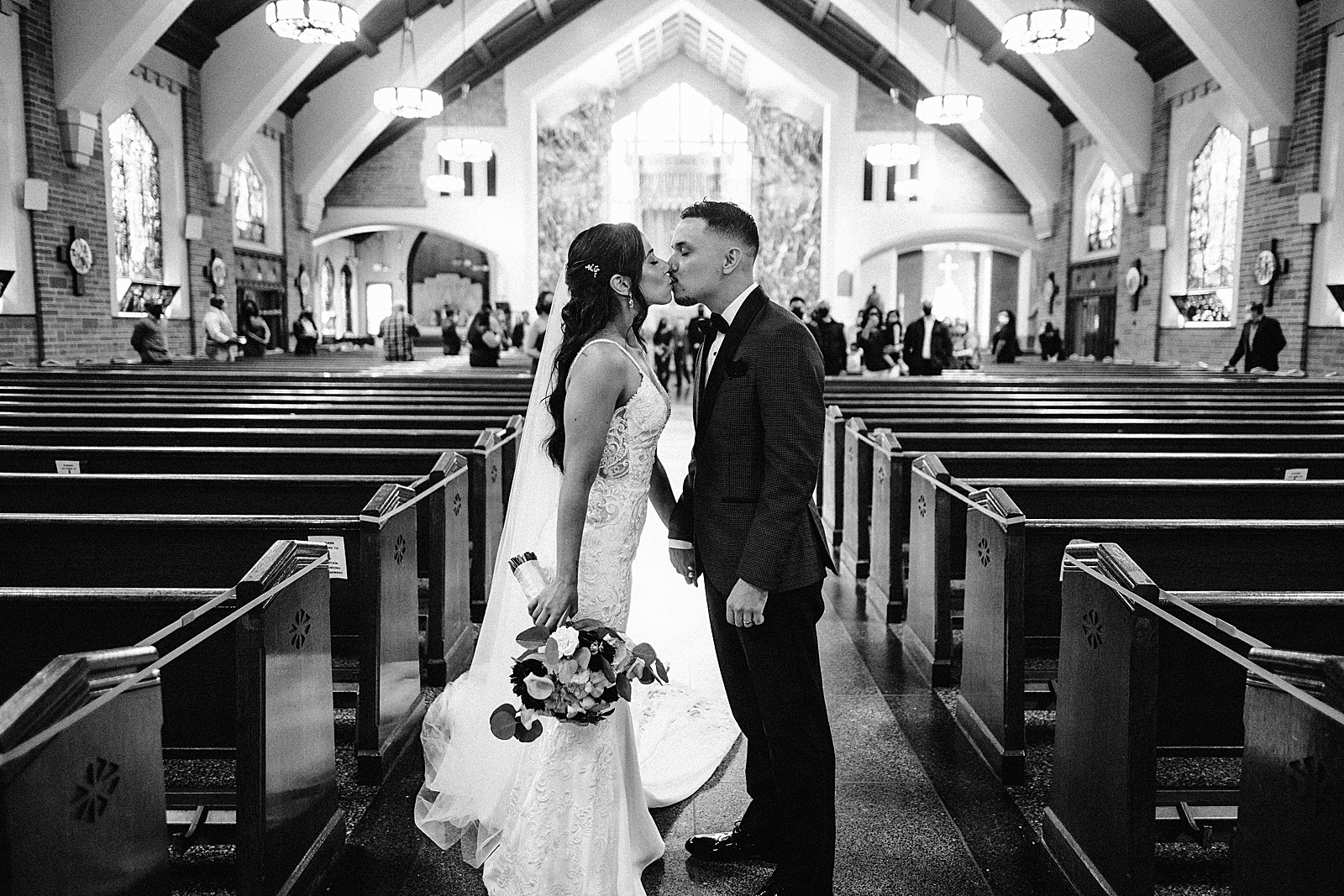 B&W Bride and Groom kissing halfway down the alter for Ceremony