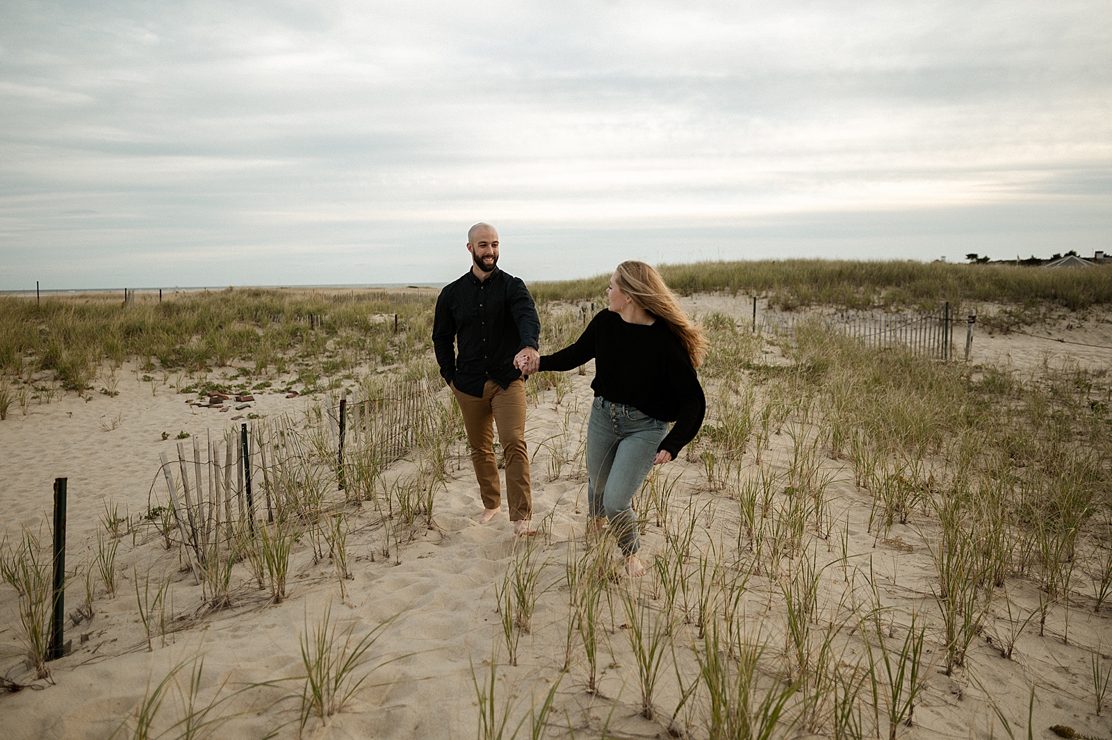 Woman holding man's hand and leading him on the sand