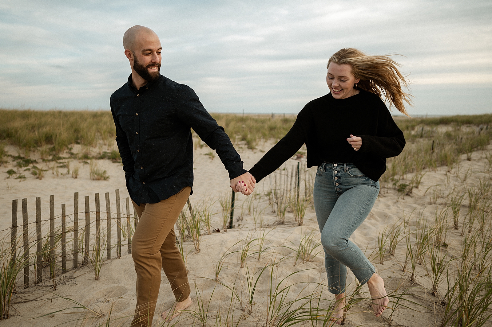 Couple holding hands and running on the sand