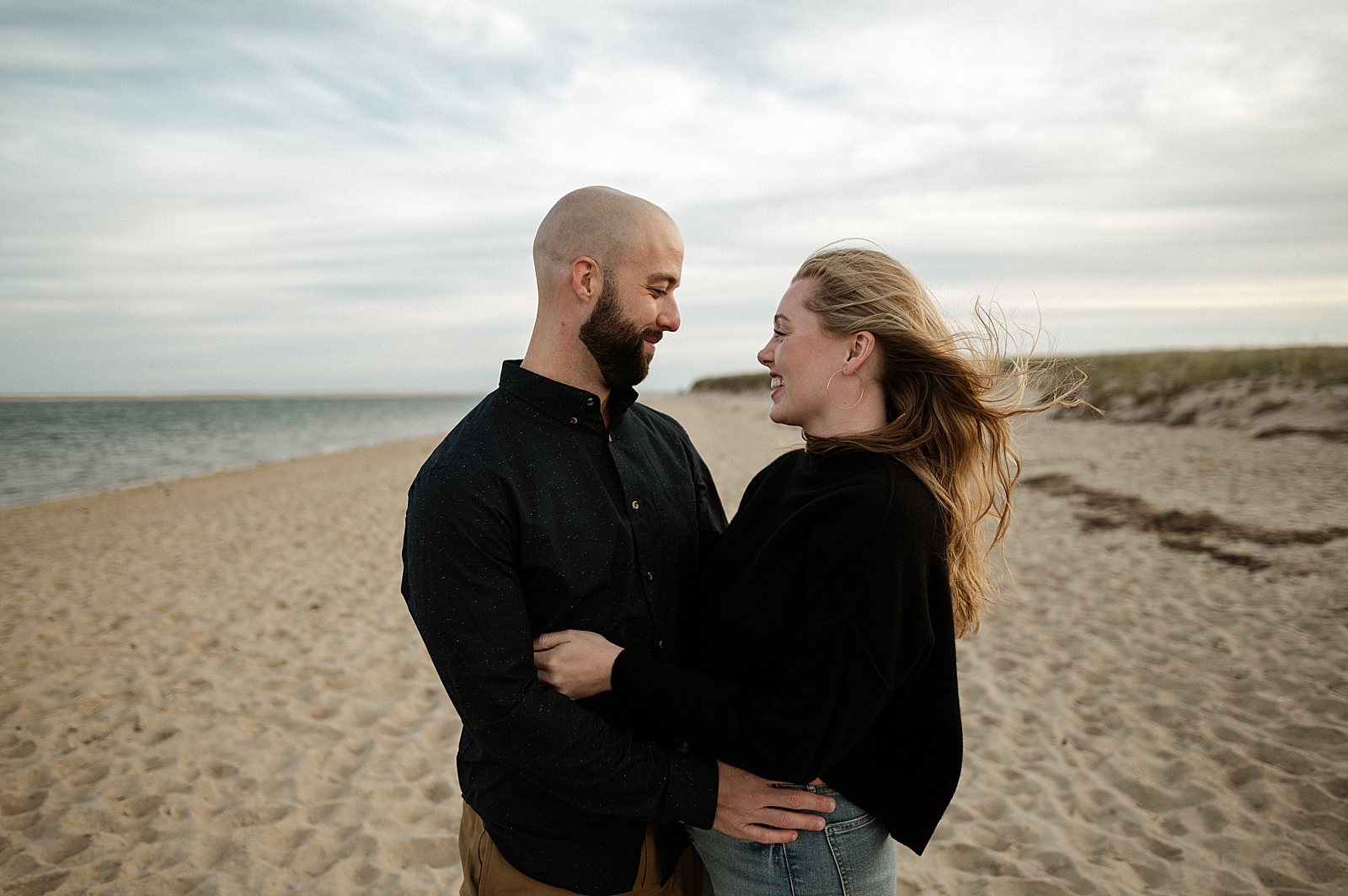 Couple hugging and looking at each other on the beach by the ocean