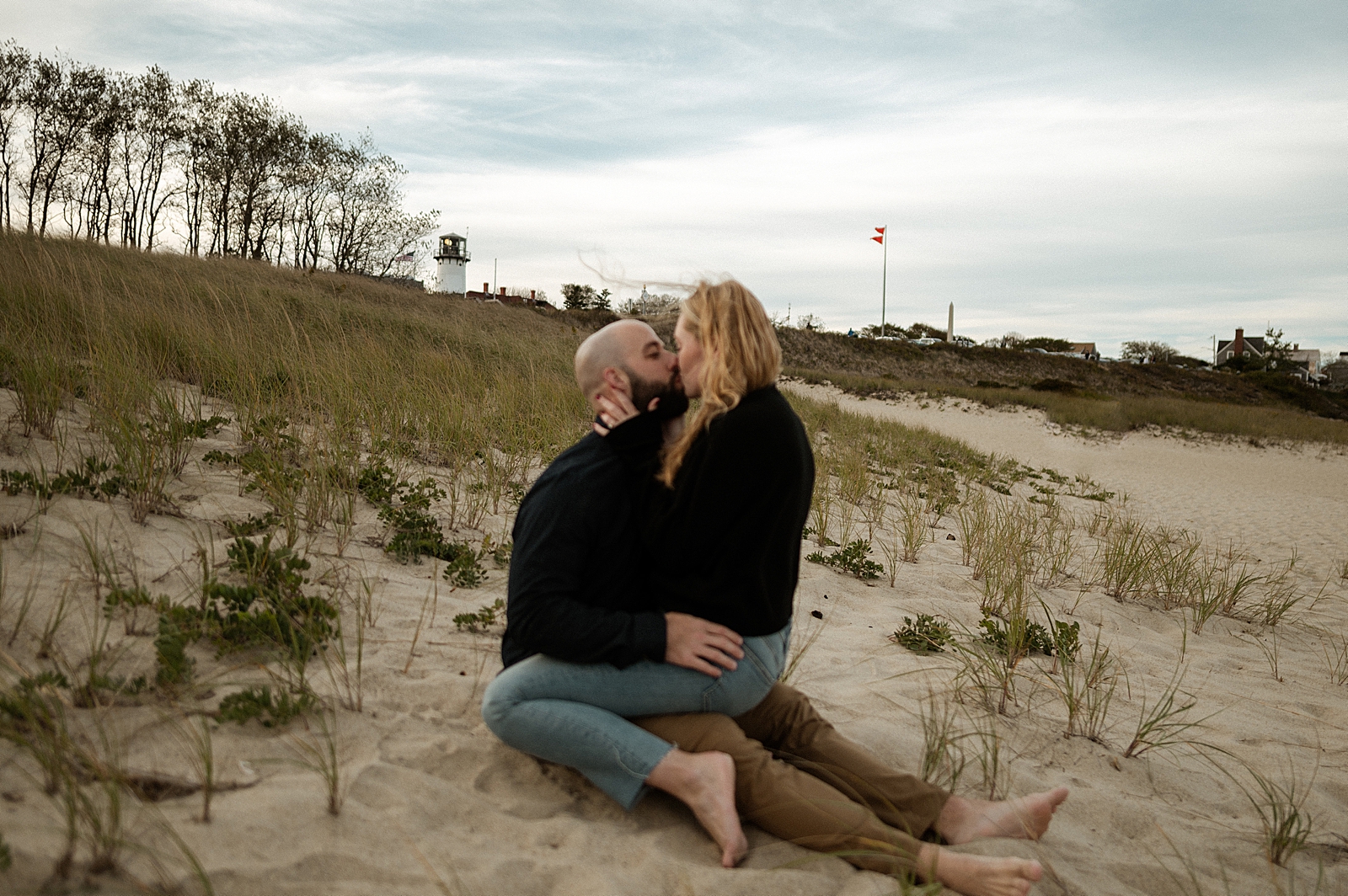 Woman straddling man on the beach and kissing on the sand