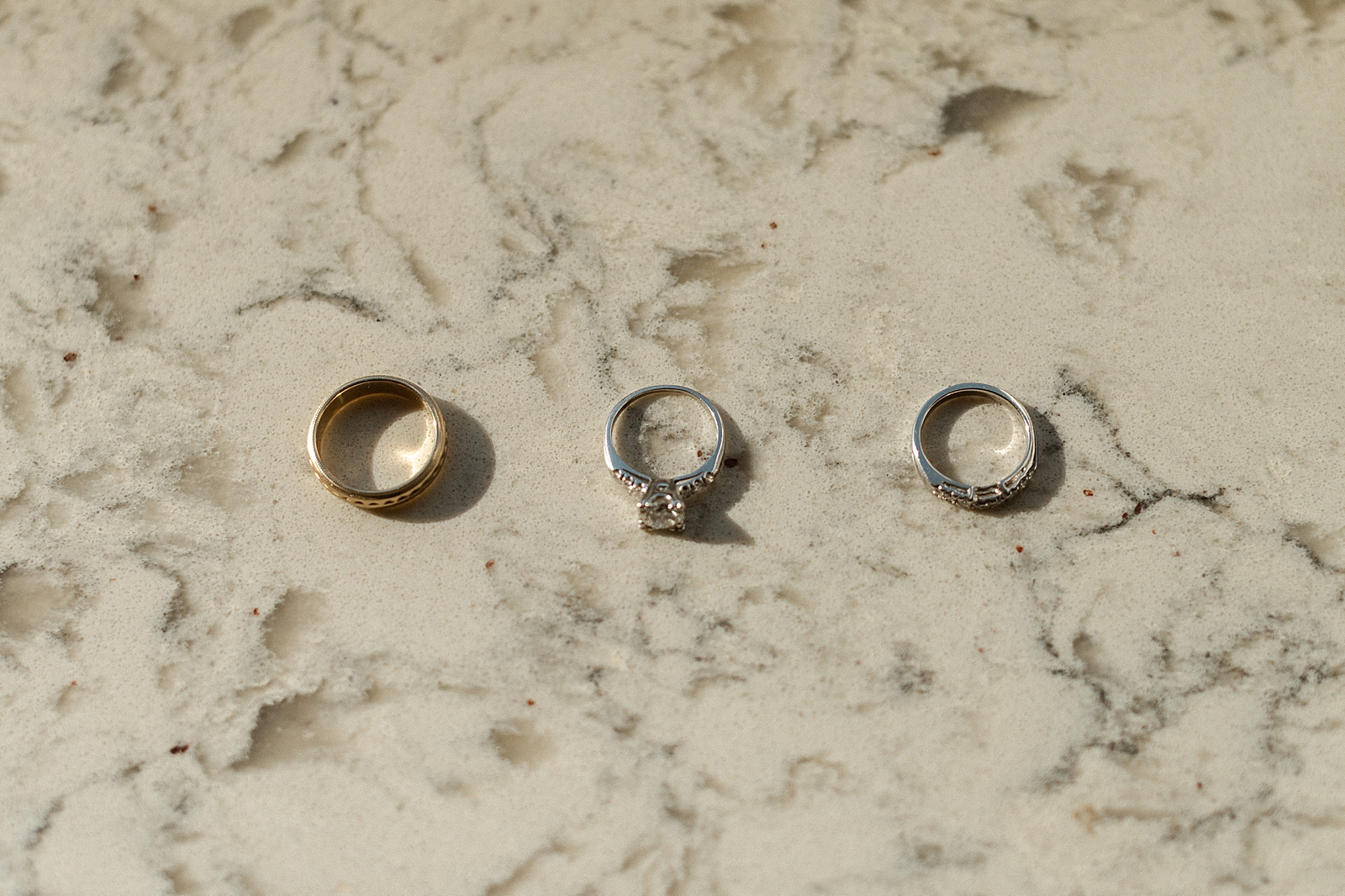 Detail shot of wedding bands and engagement ring on marble