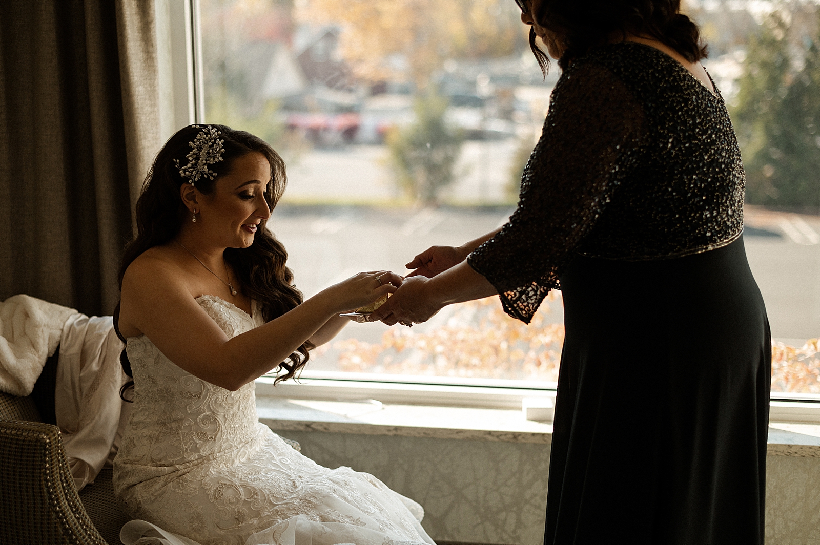 Bride receiving something from friend while getting ready