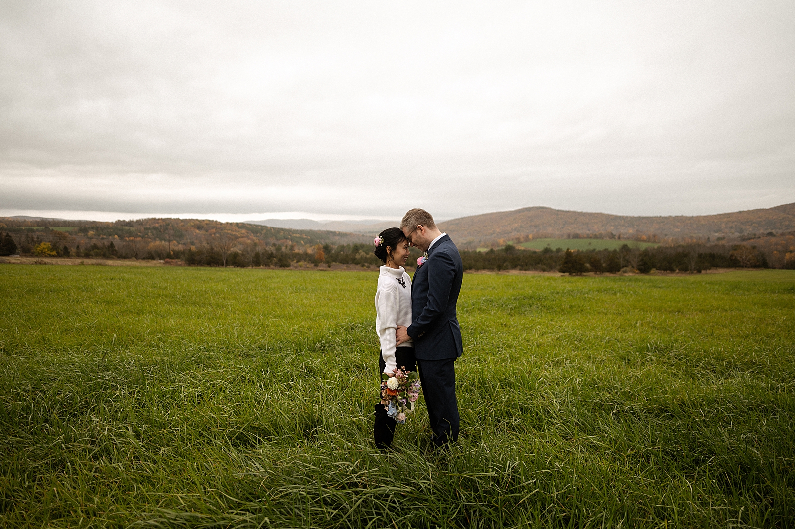 Bride and Groom resting their heads against each other on tall grassy field