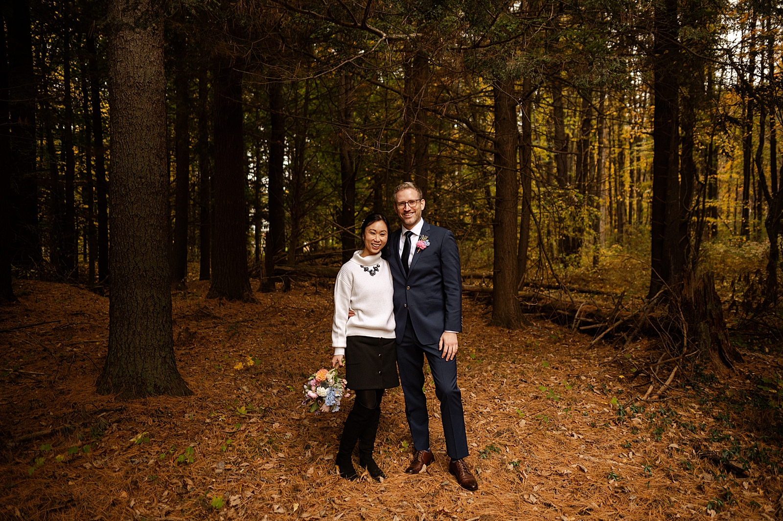 Bride and Groom standing next to each other for formal portrait in autumn forest