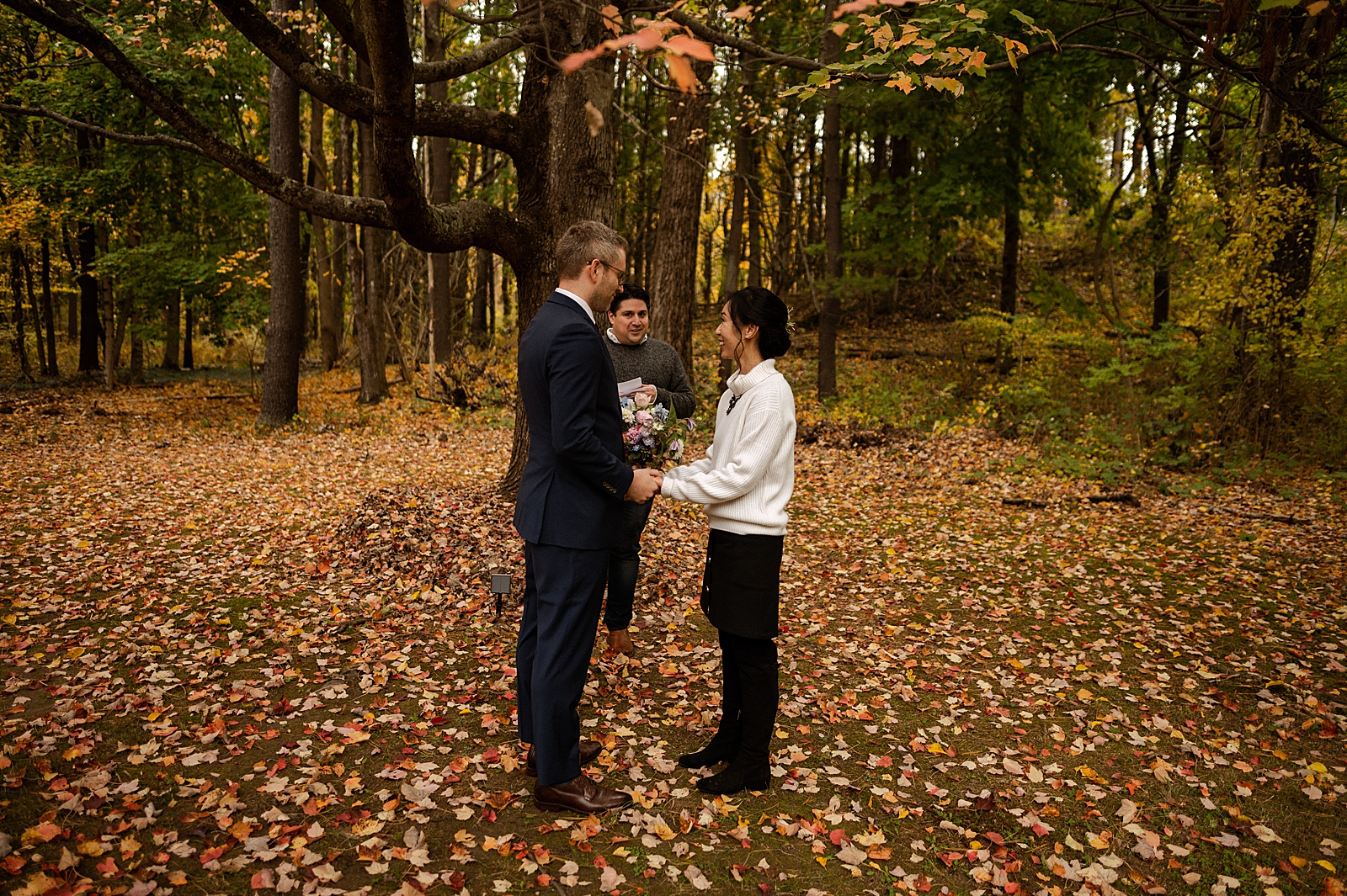 Bride and Groom hand in hand for elopement ceremony in autumn forest
