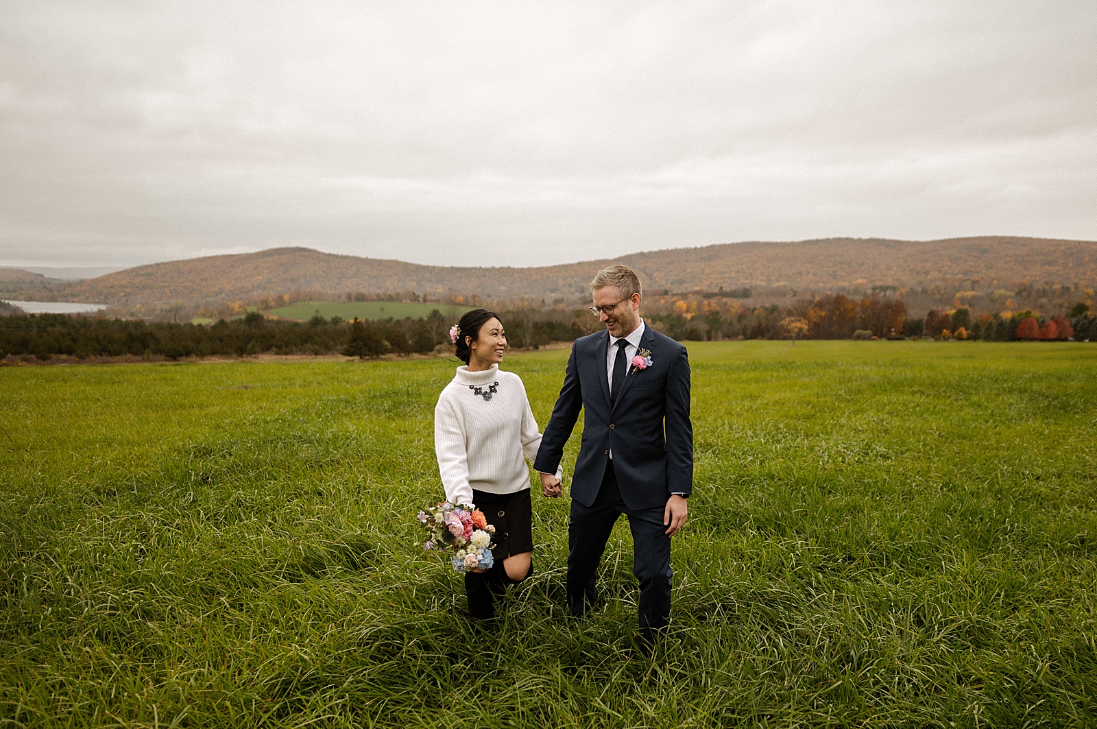 Bride and Groom holding hands walking in tall grass