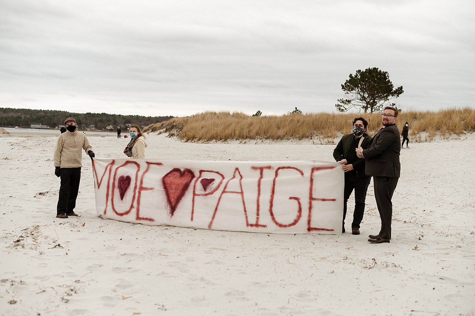 Friends and Family holding up Bride and Groom sign on the beach