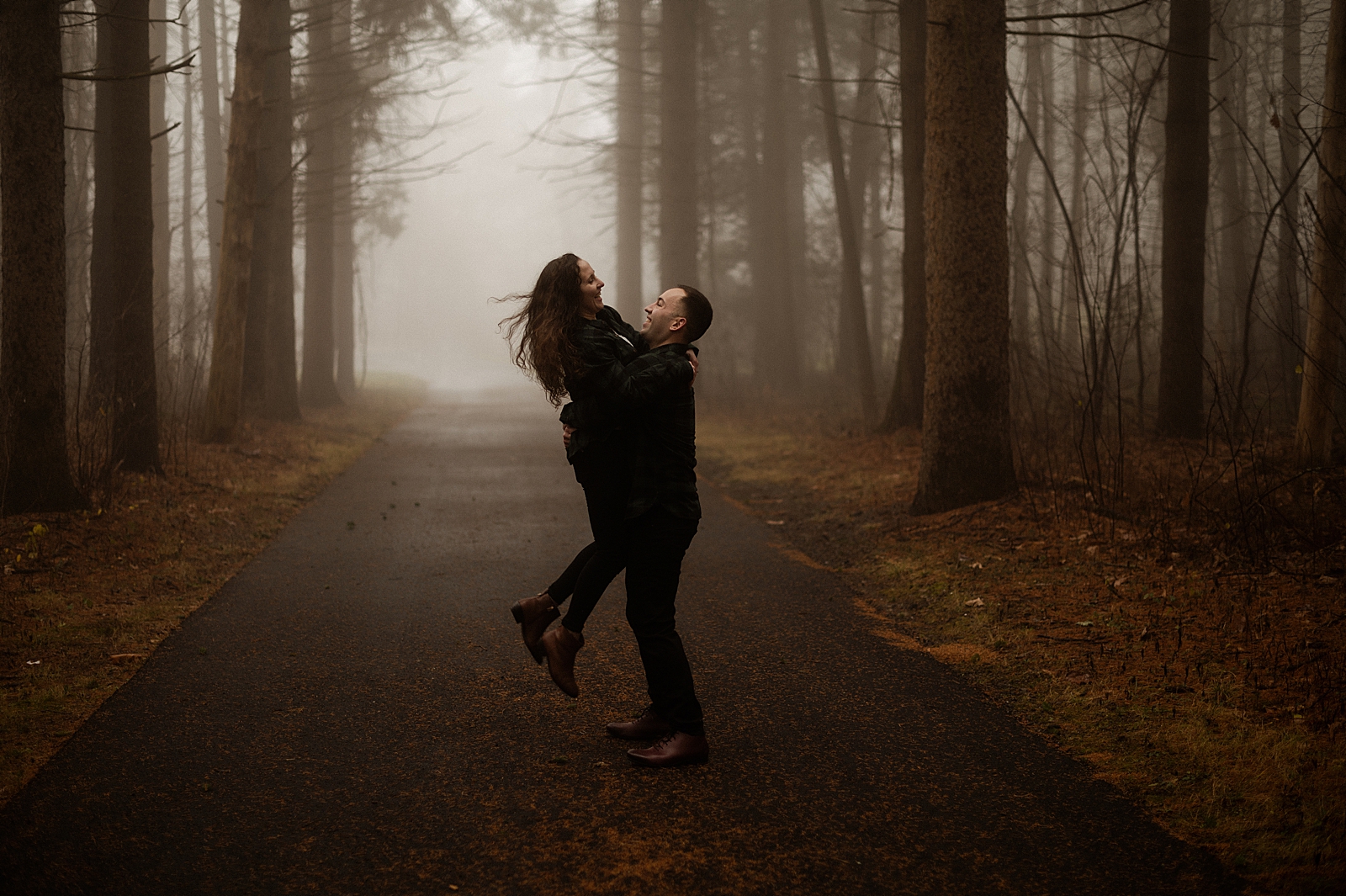 Man holding woman up in dark misty forest