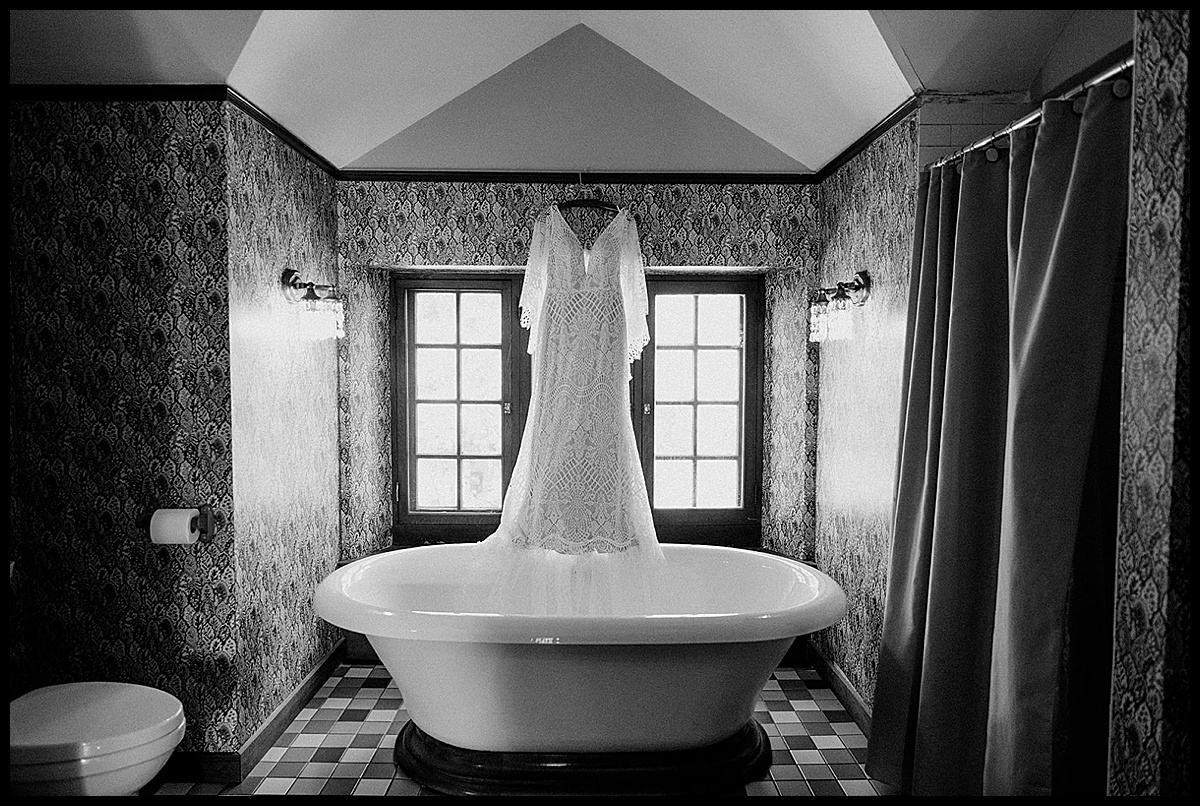 BHLDN wedding gown hanging in window over tub
