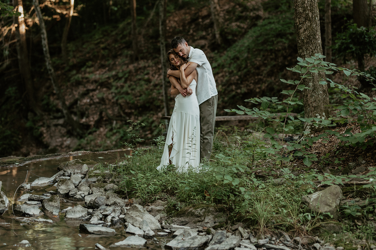 Bride and groom by stream during portraits at Grateful Woods Wedding